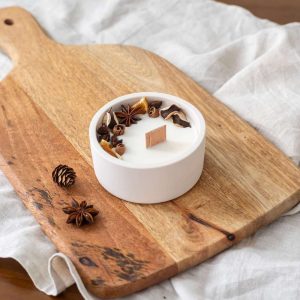Bougie artisanale décorée de fleurs séchées et bâtons de cannelle, pot en céramique naturelle, ambiance Noël